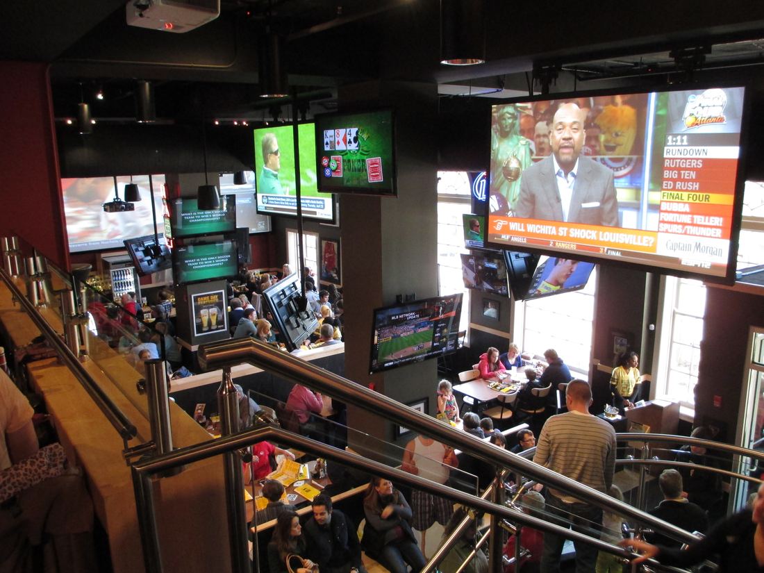 Intérieur d'un Buffalo Wild Wings : bar et mur d'écrans sportifs